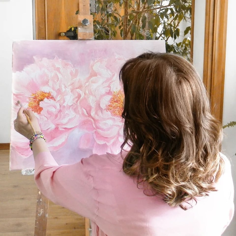 Artista che dipinge peonie rosa al cavalletto